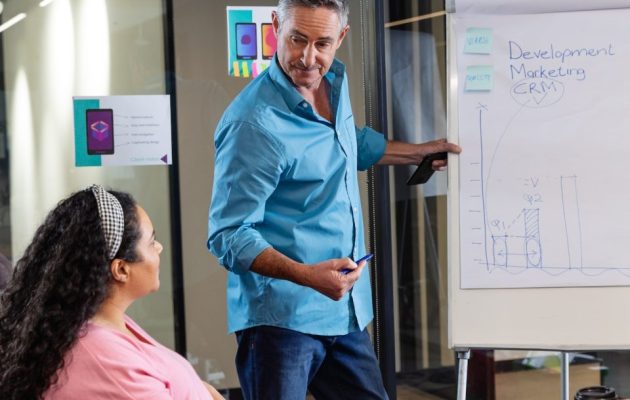 mature-caucasian-businessman-explaining-strategy-to-colleagues-over-flipchart-in-meeting-at-office-e1669550336626