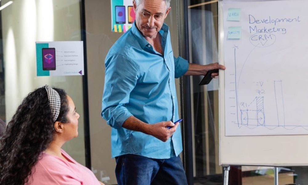 mature-caucasian-businessman-explaining-strategy-to-colleagues-over-flipchart-in-meeting-at-office-e1669550336626